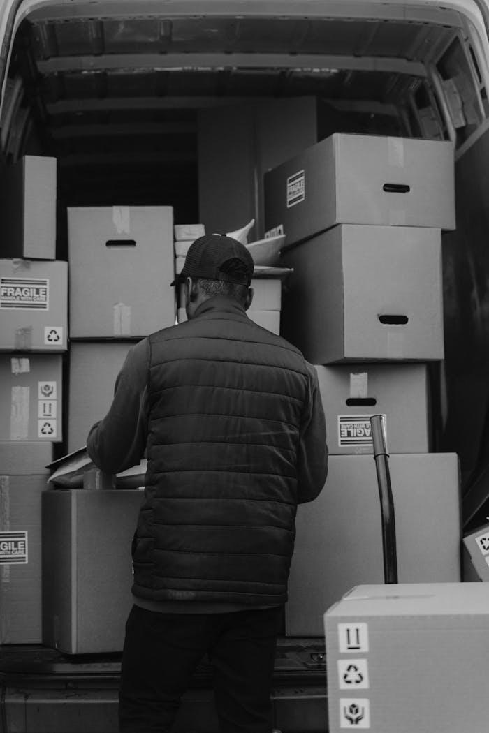 Black-and-white photo of a courier arranging boxes in a delivery van.
